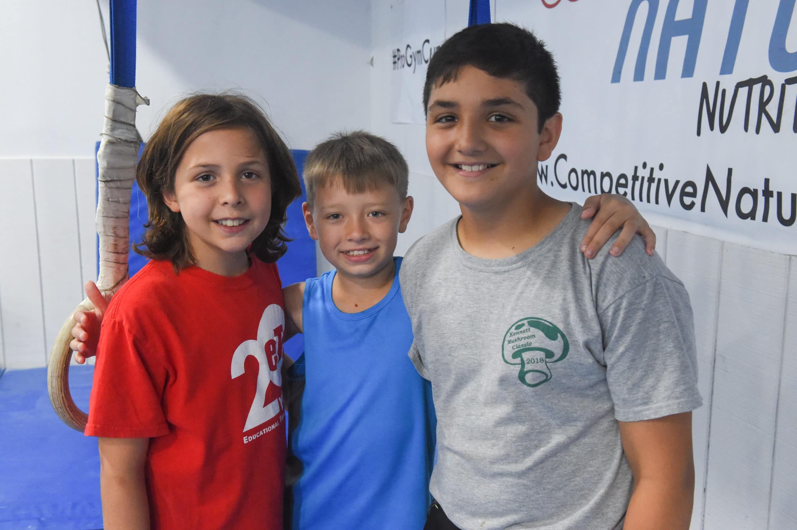 Three campers pose for a photo together in front of the rings.