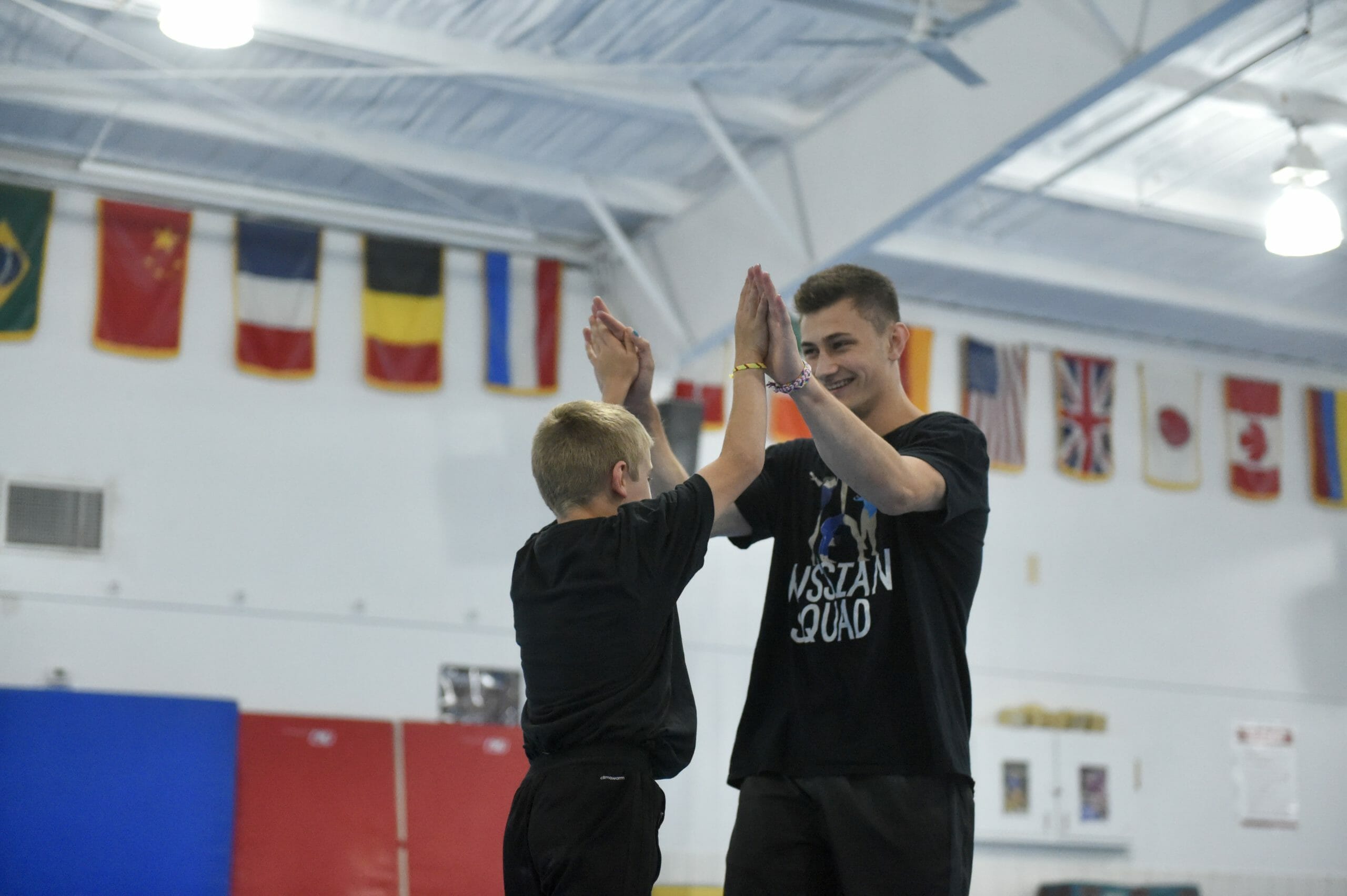 young male gymnast high fiving coach