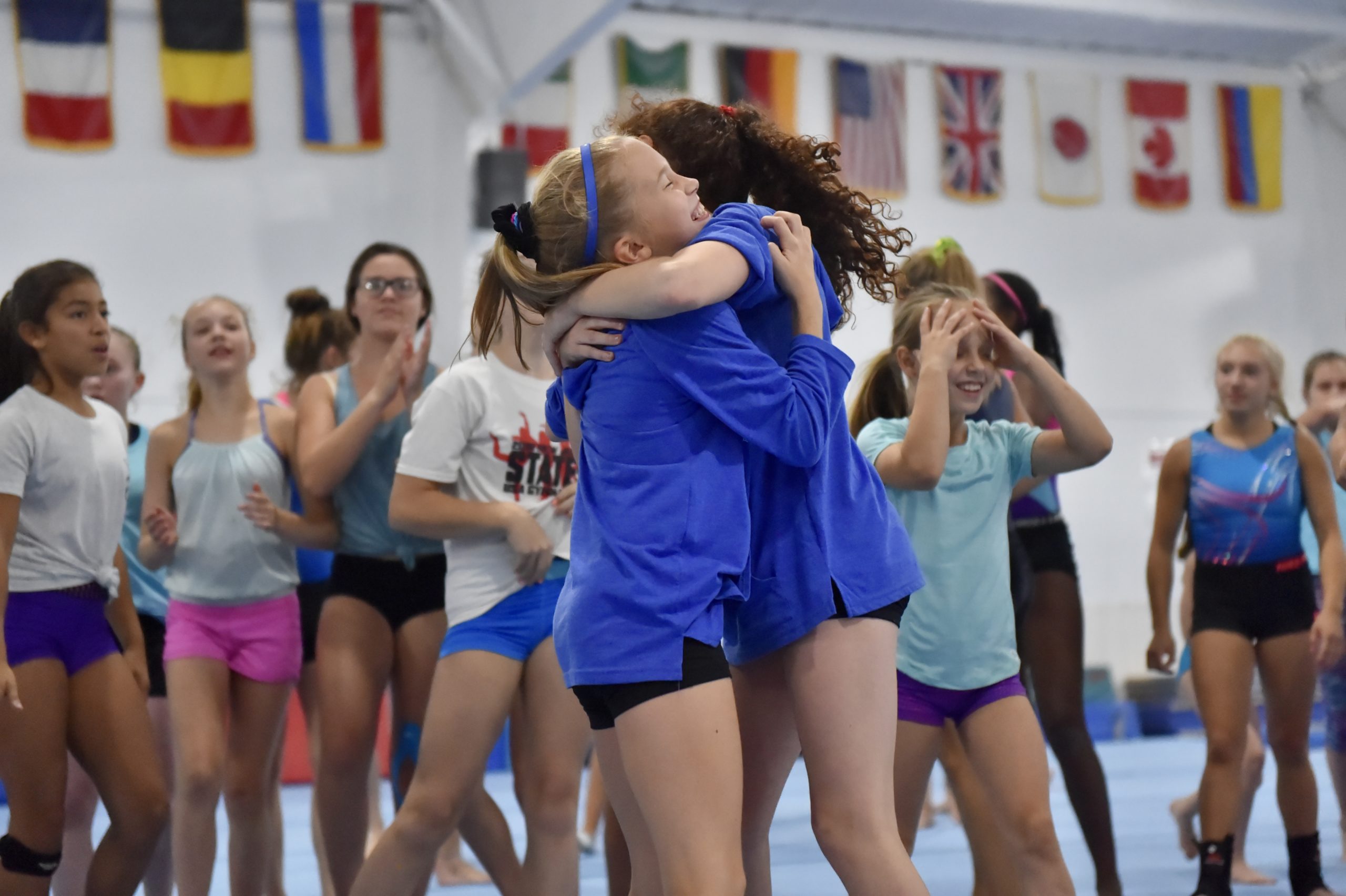 Two campers hug each other in celebration as other campers look on.