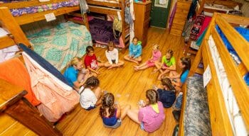 counselors and campers sitting in a circle on the floor of one of the cabins