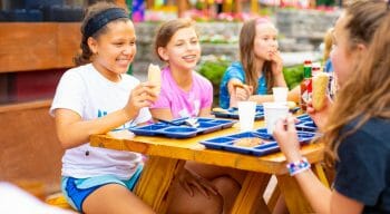 campers eating and socializing outside at the picnic tables