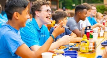 counselors eating and socializing outside at the picnic tables by the cafe