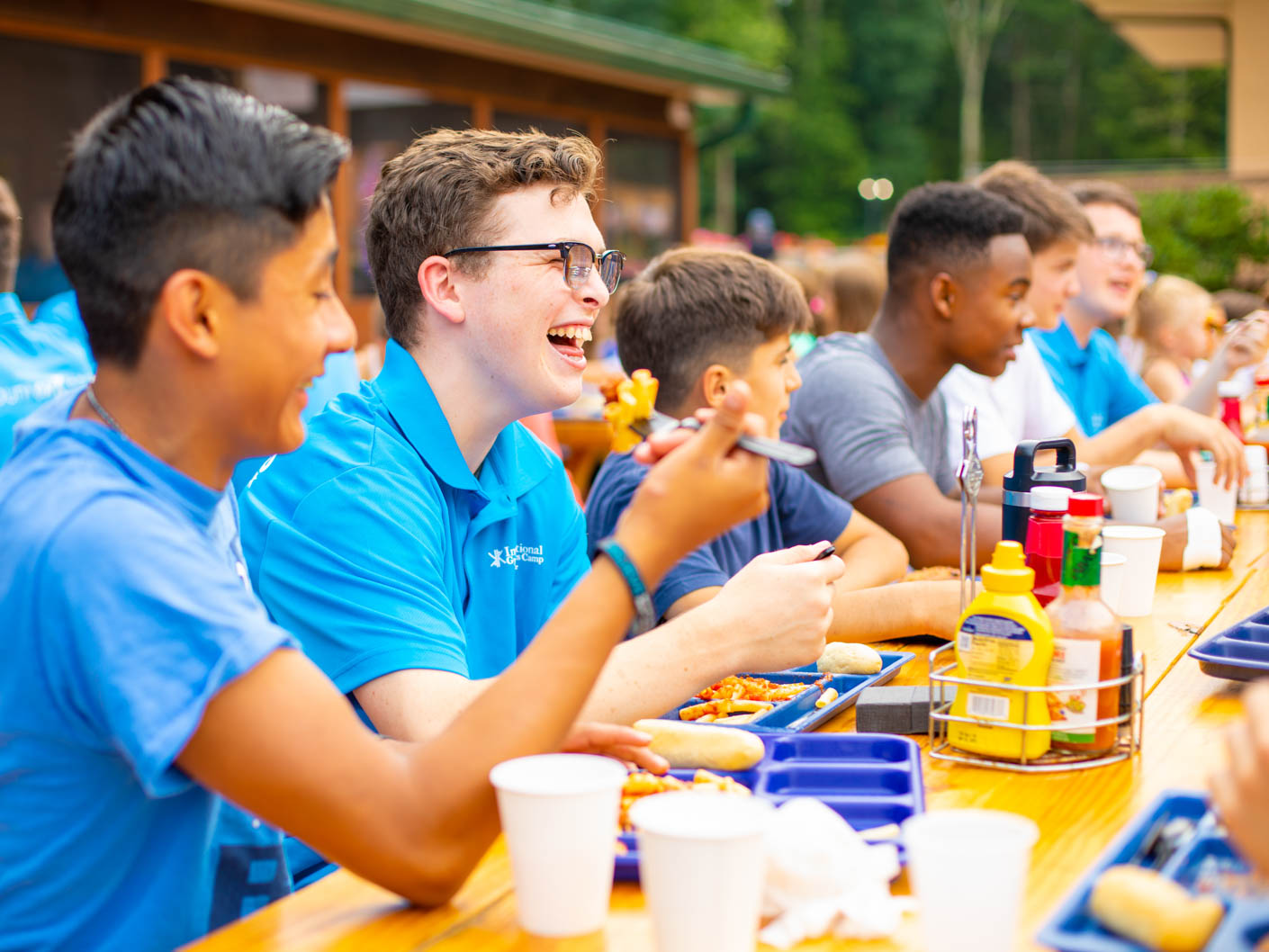 counselors eating and socializing outside at the picnic tables by the cafe