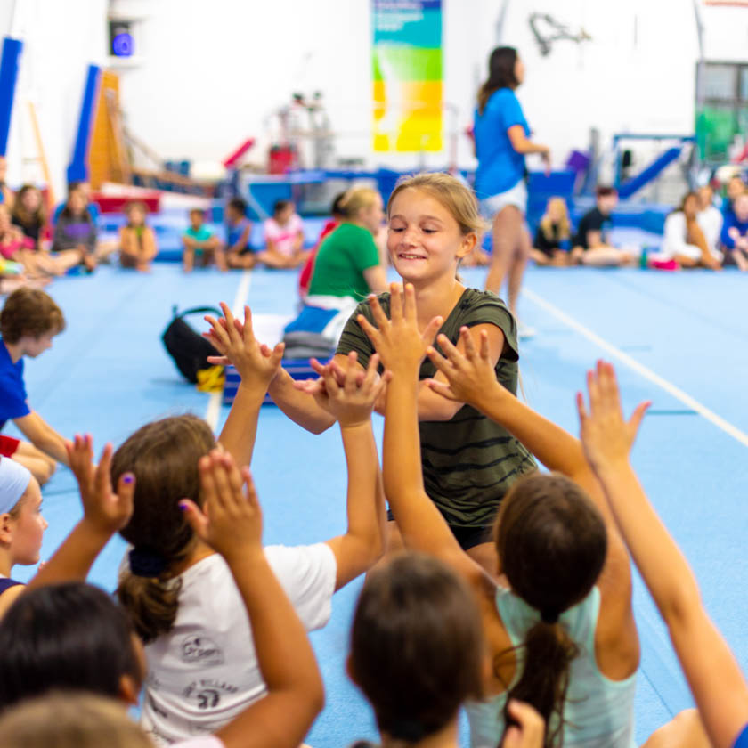 gymnast high-fiving a group of fellow gymnasts