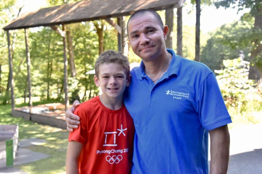 RUSTAM SHARIPOV poses with his arm around a young camper.
