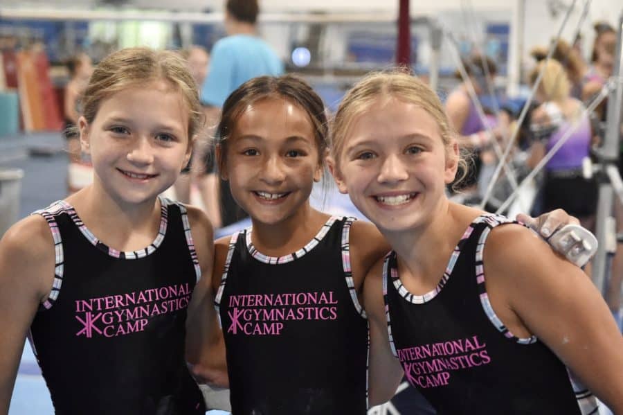 3 gymnasts smiling in leotards