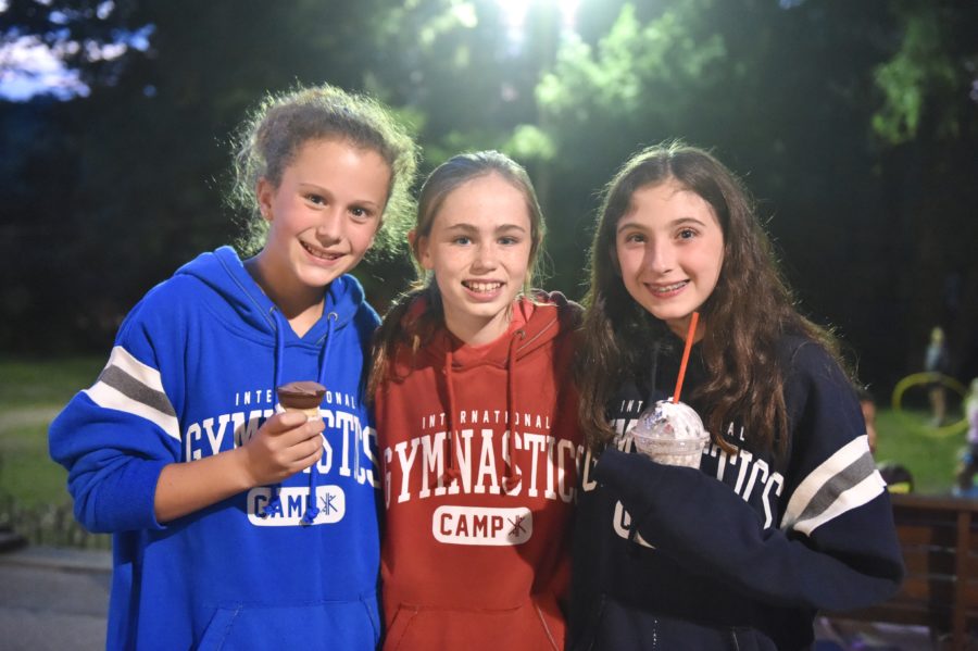 Three campers enjoy ice cream from the camp store while wearing IGC sweatshirts.