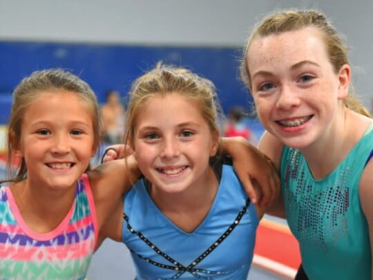 three girls with arms around each other at gymnastics camp