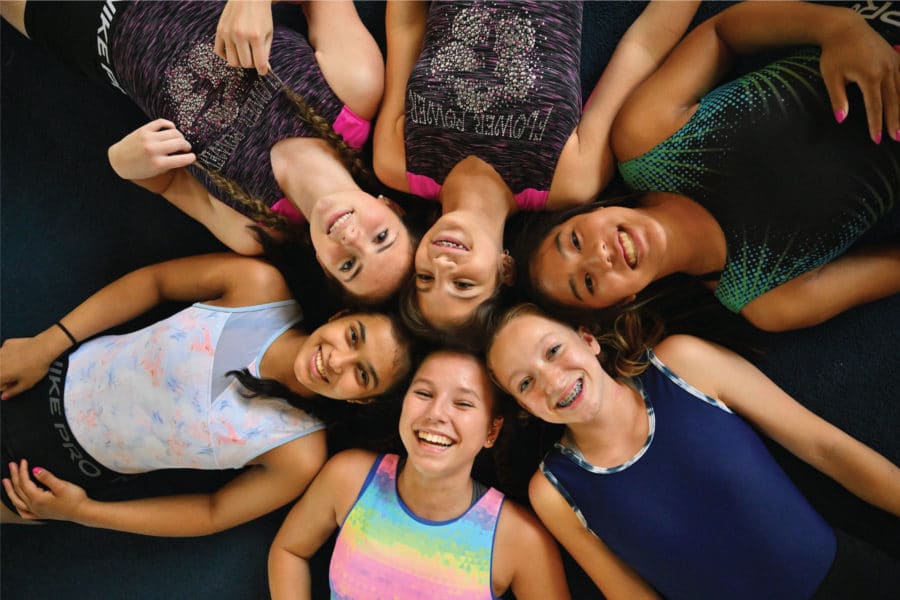 girls laying in a circle on the floor smiling